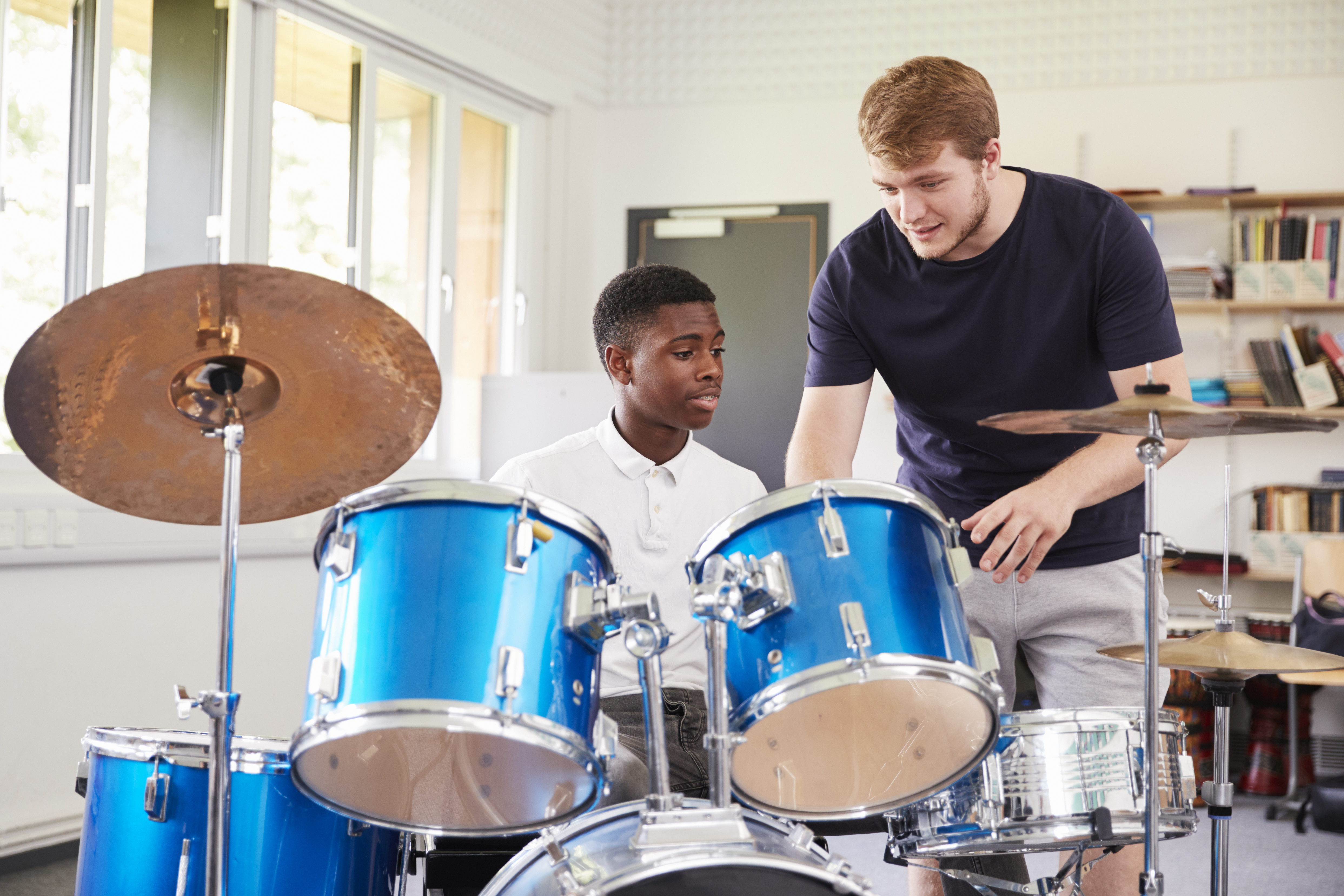 Drum instructor guiding a student at a full drum kit