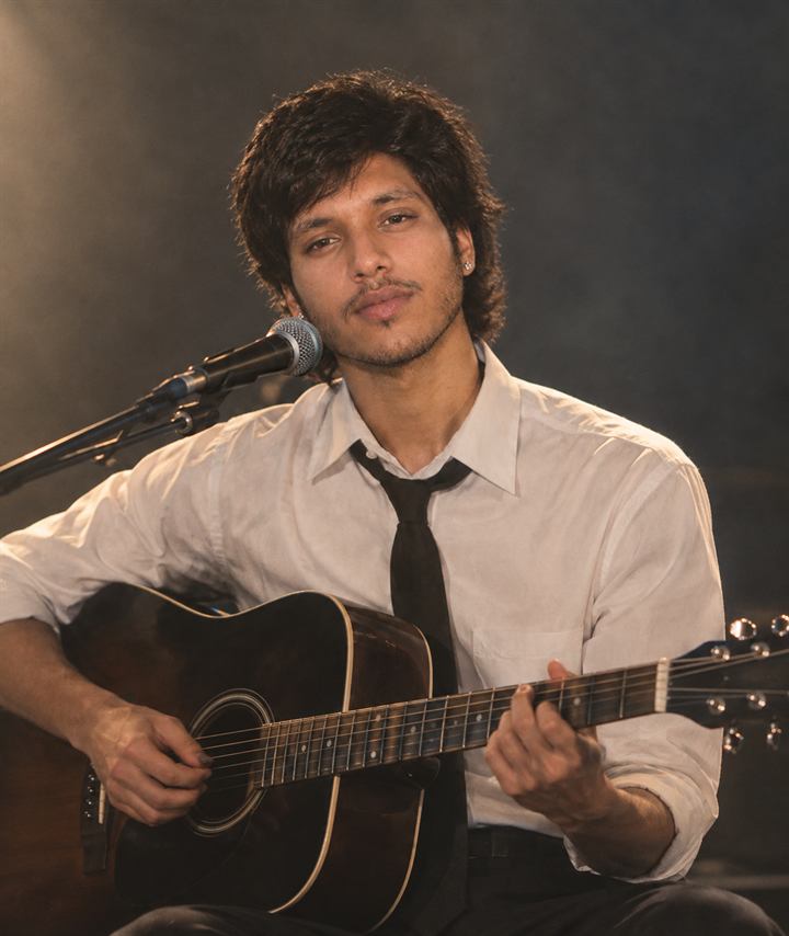 Rocksmith Records instructor playing acoustic guitar at a microphone